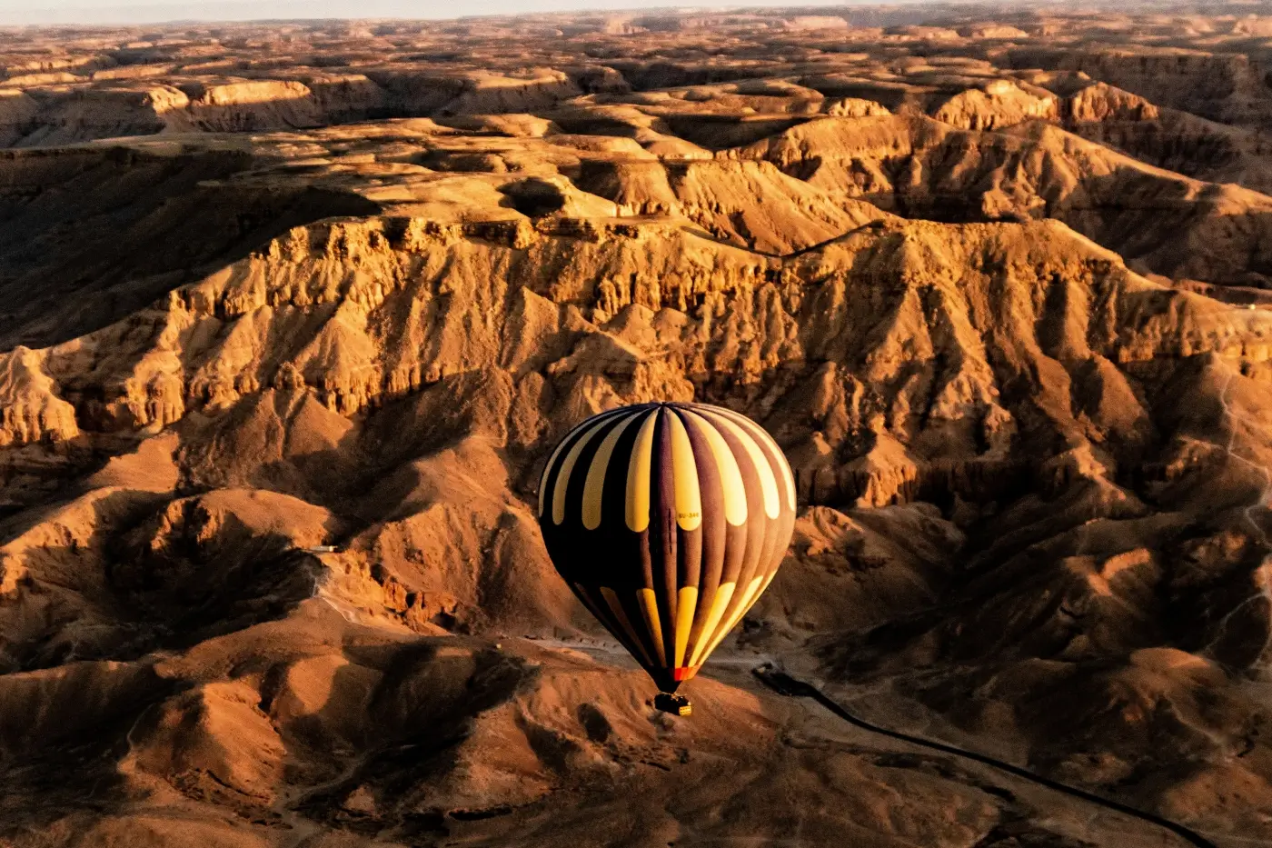Globo aerostático sobre las colinas desérticas de la orilla occidental de Luxor al amanecer